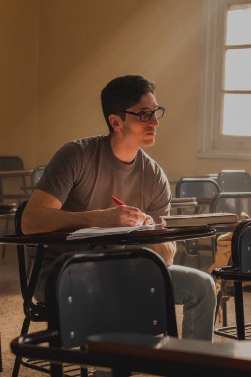 Alumno adulto tomando apuntes con un boli rojo en clase