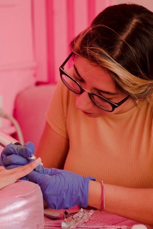 Manicurista trabajando con torno y guantes en el estudio